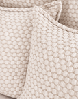 White matelasse bedding fabric with raised geometric texture close-up.
