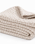 Folded white matelasse quilt with stacked layers and textured surface.