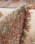 Decorative pillow fabric close-up with mottled weave and fringed trim
