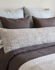 18x60 body pillow in ivory with speckled fabric on a bed