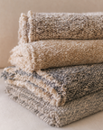 Brentwood textured throw blanket with fringe trim, shown folded in pebble and ocean tones