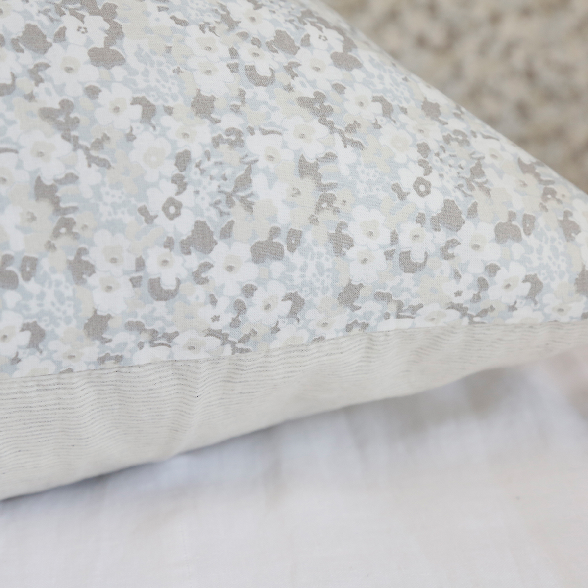 Light gray floral print pillow close-up, stitched edge and textured fabric