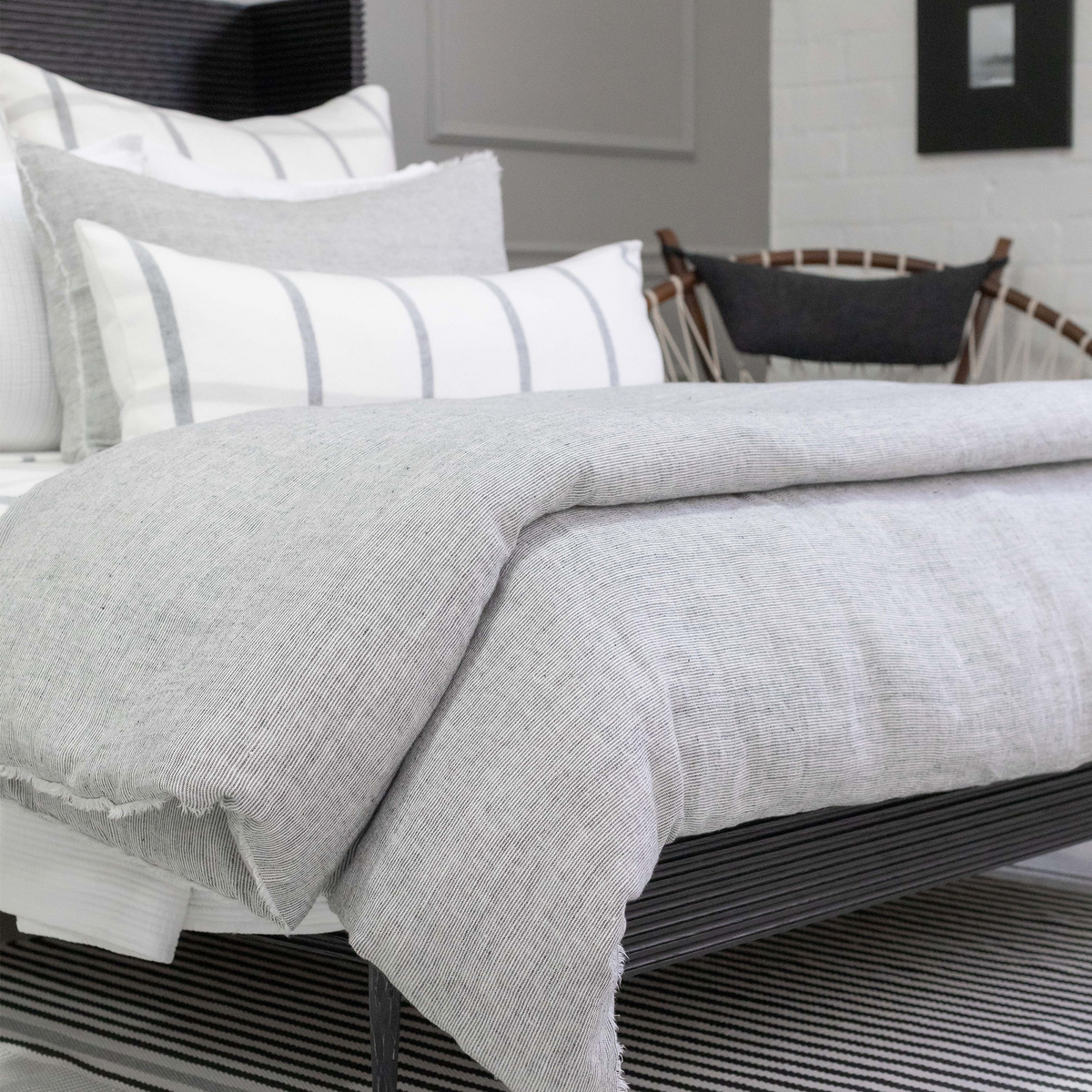 Light gray woven throw blanket with soft fringed edge draped over sofa bed