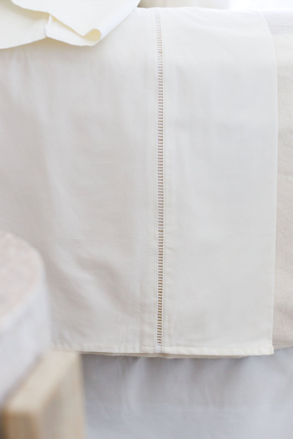 White fitted sheet with ladder-stitched panel along the corner seam