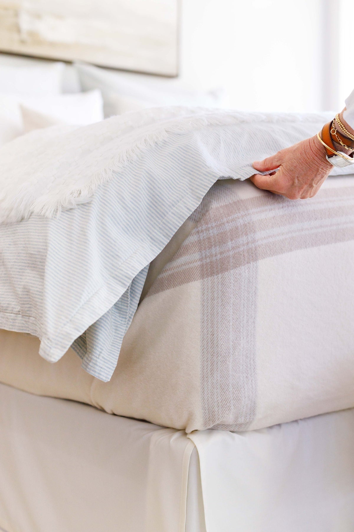 Geneva blanket draped over bedding in white with beige plaid stripe border