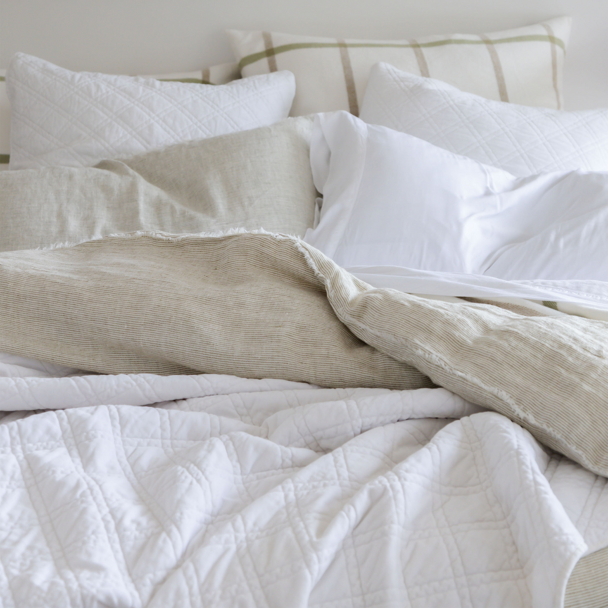 Taupe linen-look coverlet with textured weave and fringed edge over white quilt