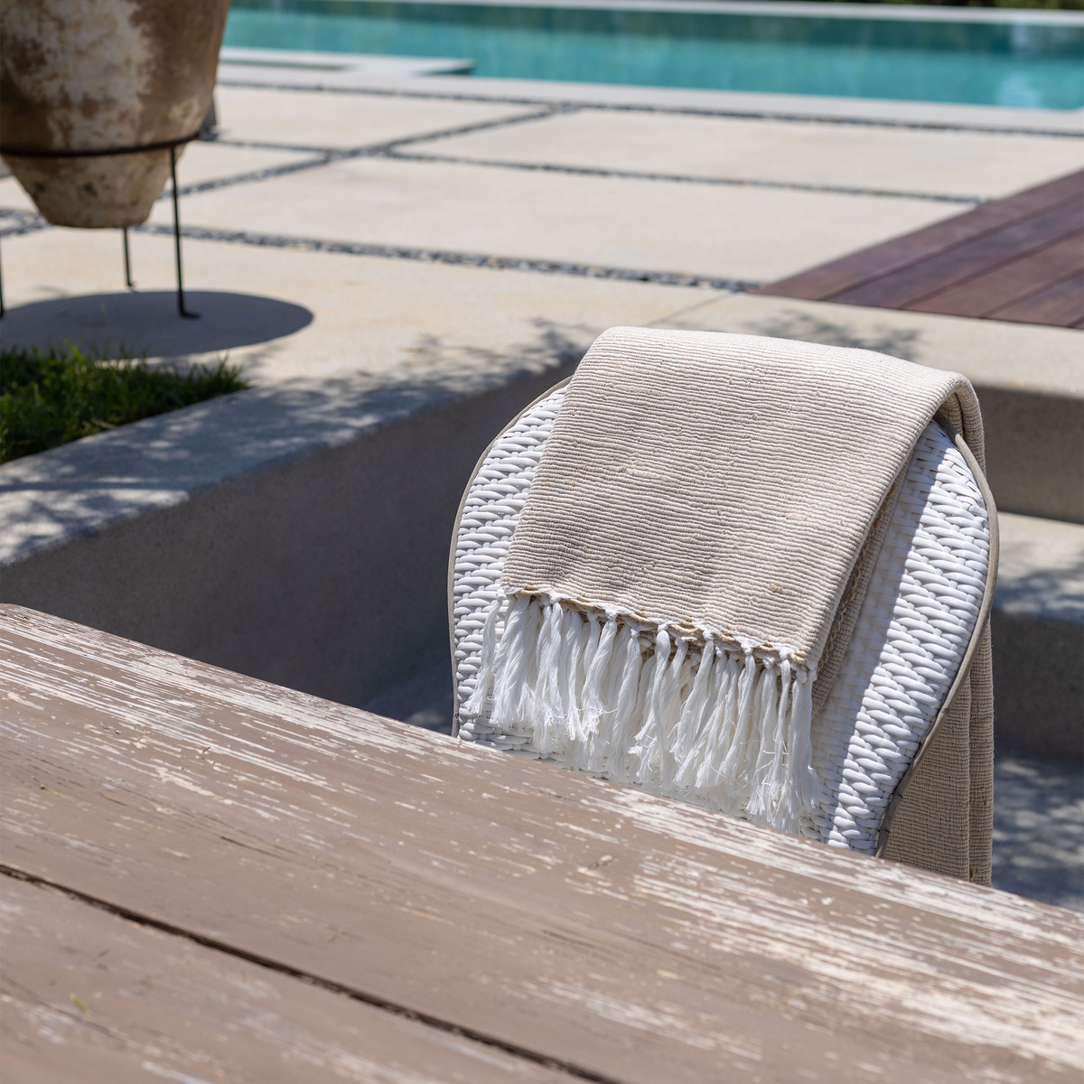 Light natural throw folded over with white tassel fringe visible at the edge