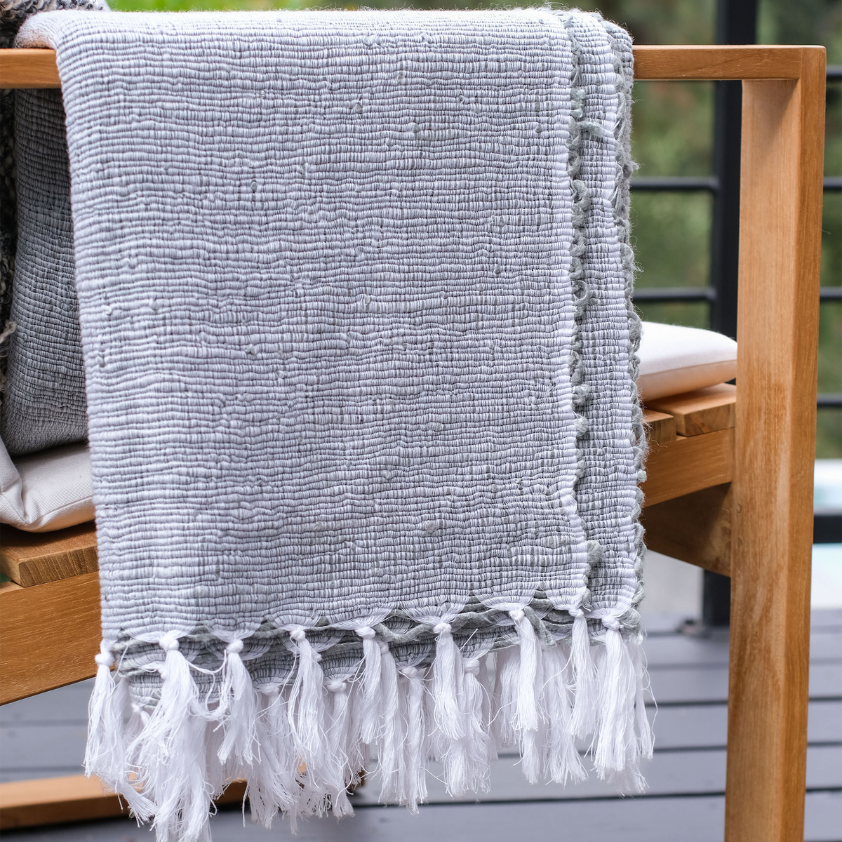 Shore Blue woven throw draped over outdoor chair arm with white tassel fringe