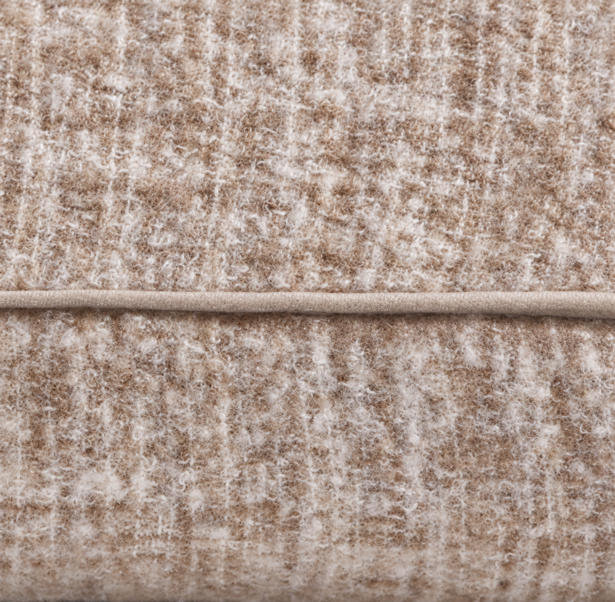 Close-up of beige textured woven pillow fabric with seam line