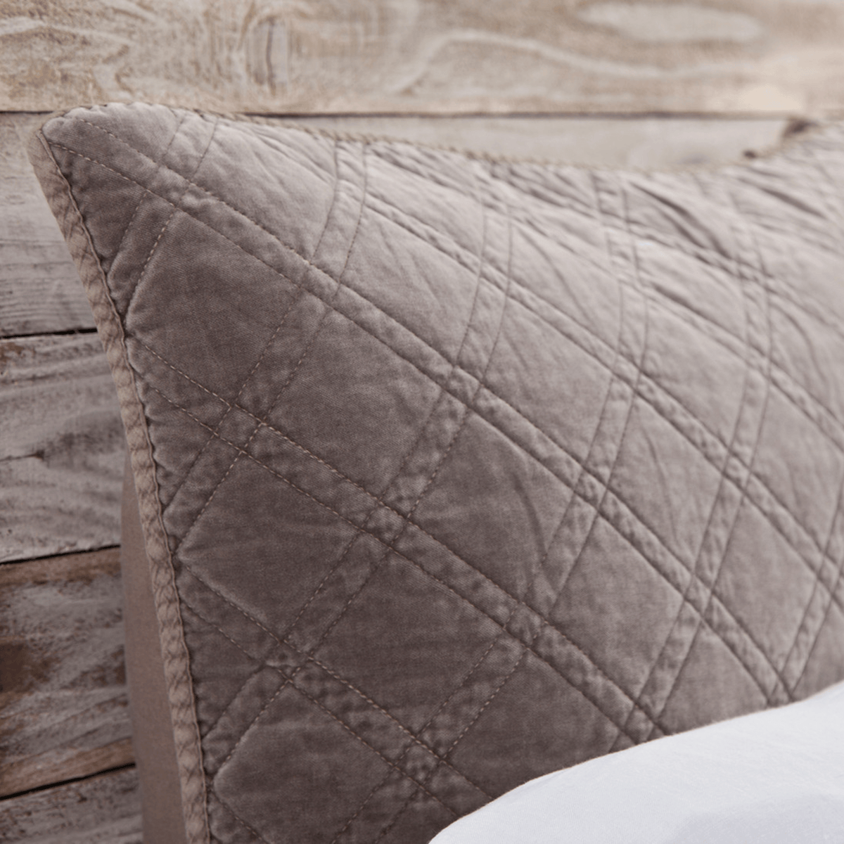 Close-up of pewter gray quilted coverlet with diamond stitch seams and texture.
