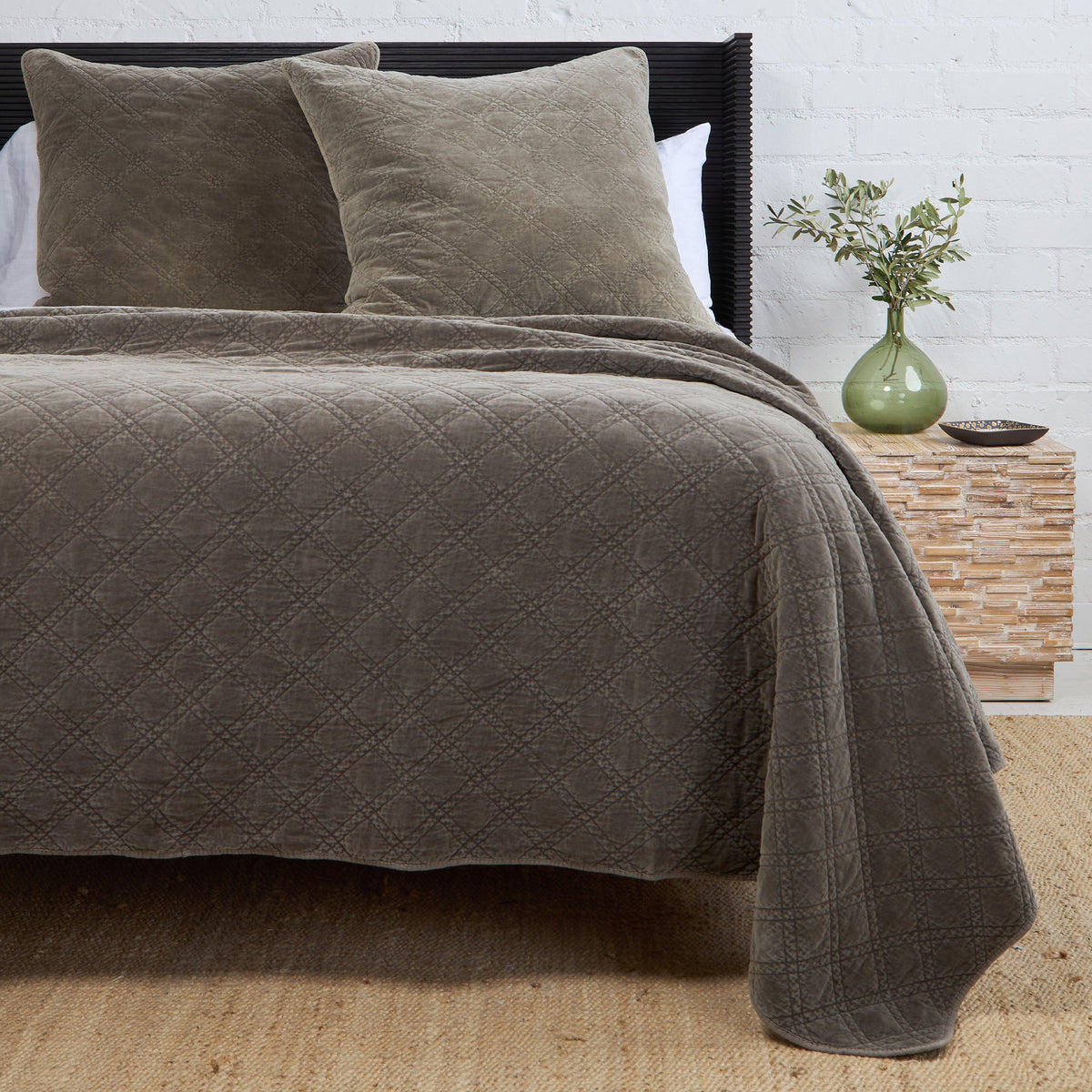 Gray quilted coverlet with diamond stitch quilting and rounded folded edge.