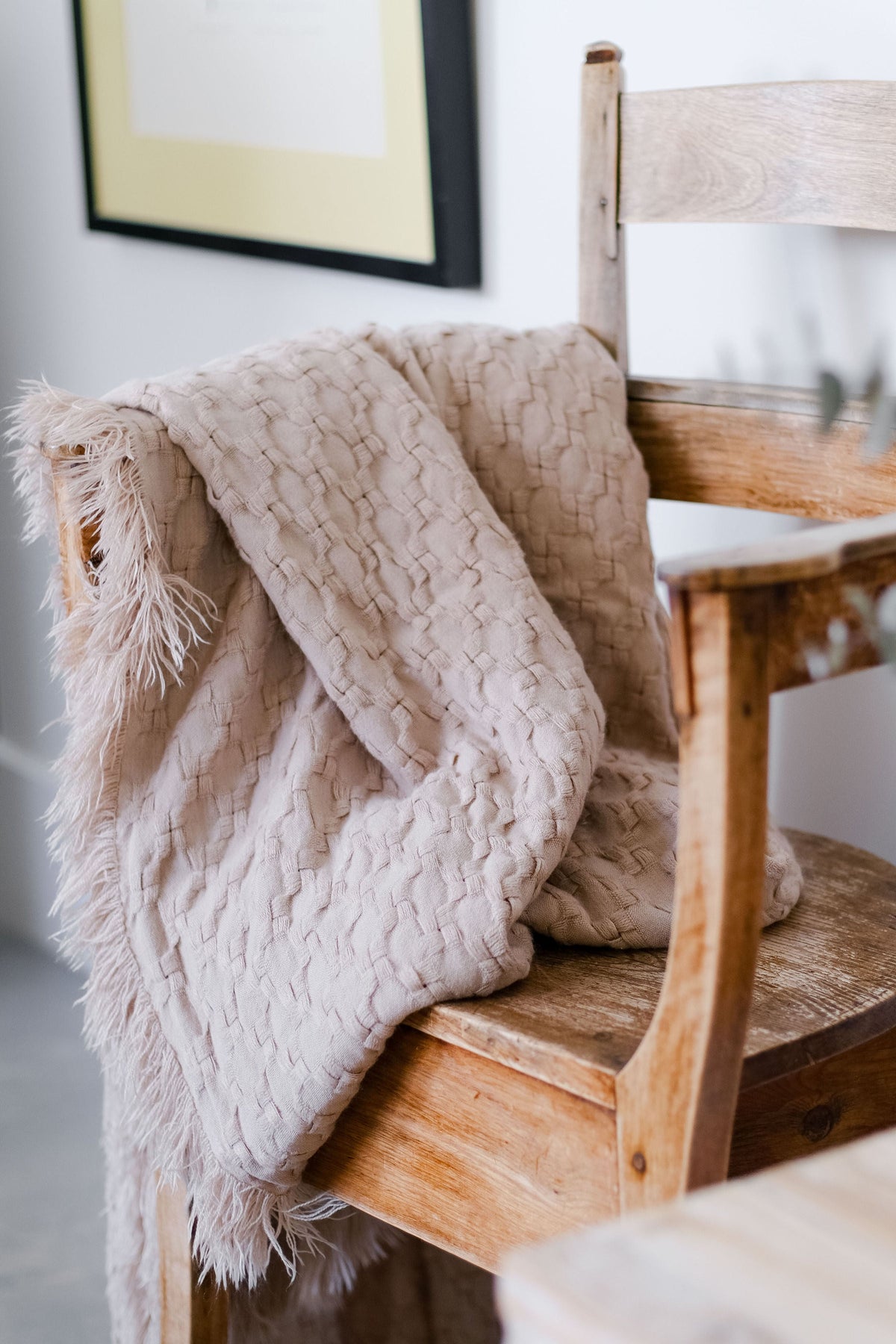 Delphine oversized throw draped on a chair with woven pattern and long fringe