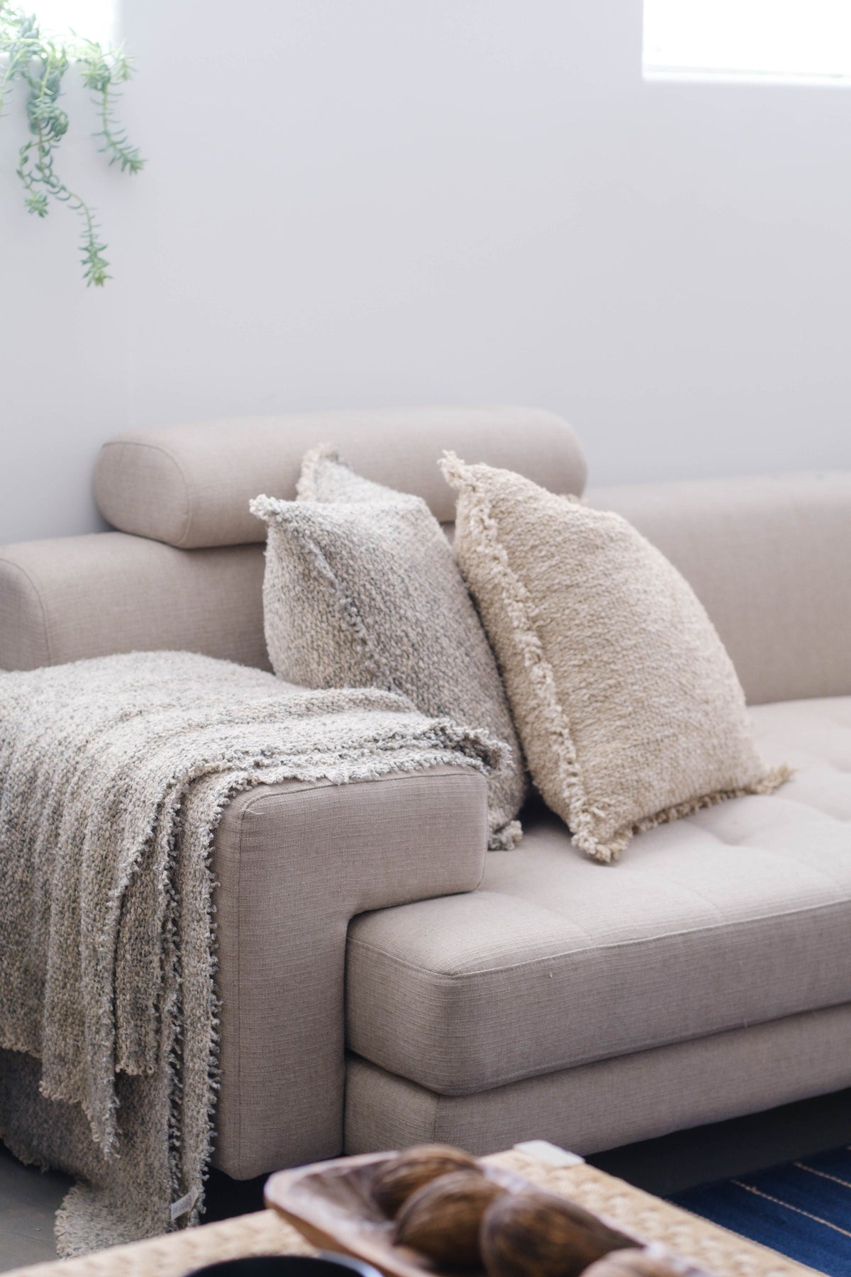 Brentwood throw blanket in textured gray with fringed ends, draped on sofa.