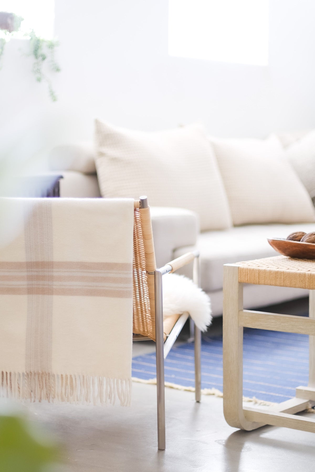 Off-white plaid throw blanket draped over a chair with fringed edge