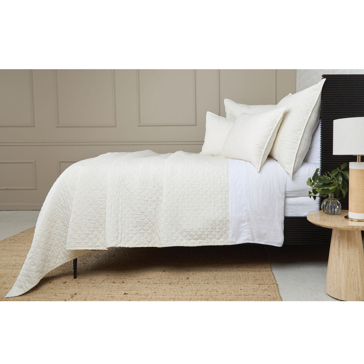 White quilted coverlet with diamond texture and stitched border detail on edge