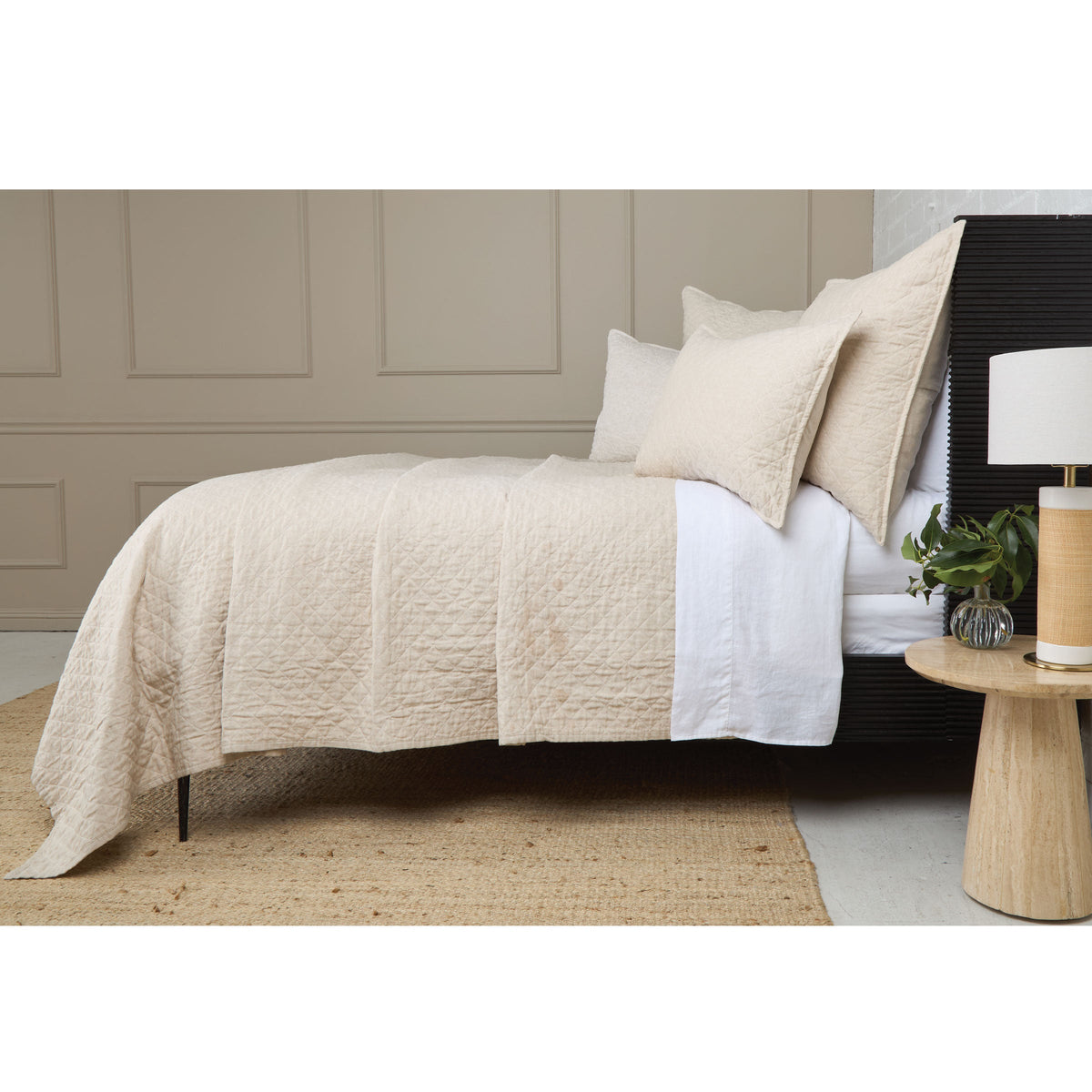 Cream quilted coverlet with diamond stitch pattern, draped across the bed