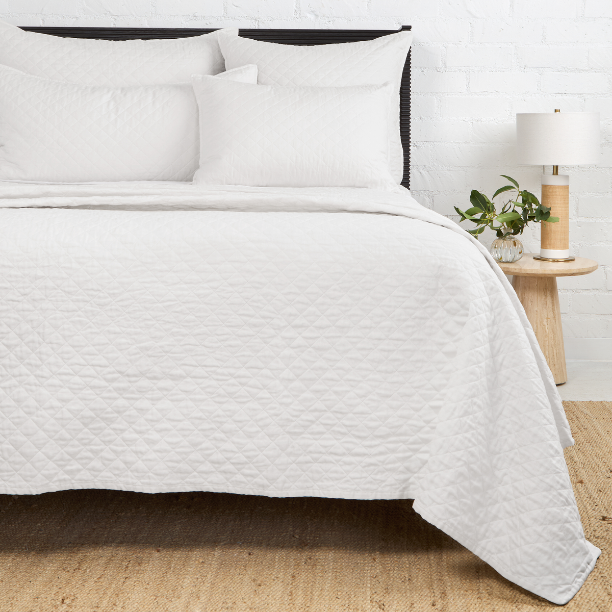 Quilted white coverlet with diamond stitch quilting, layered over pillows