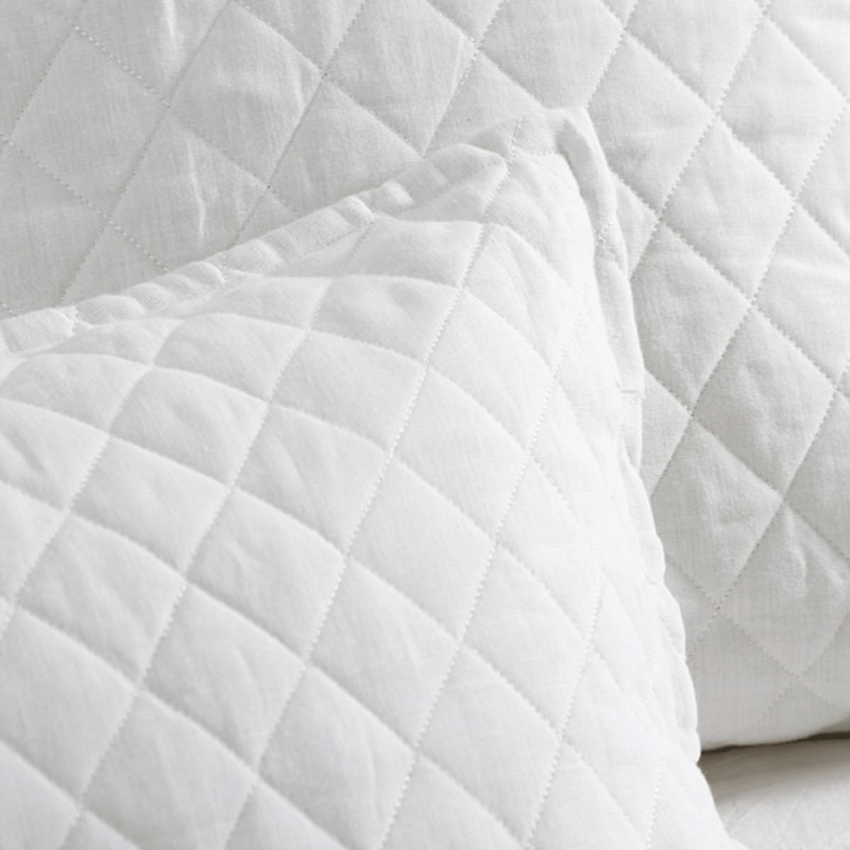 Close-up of white coverlet quilting with continuous diamond stitch pattern