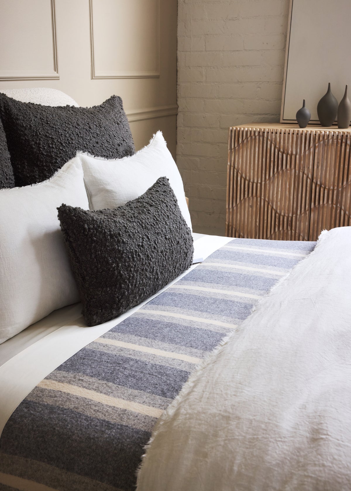 Striped woven blanket on bed with dark gray, white, and light blue horizontal stripes