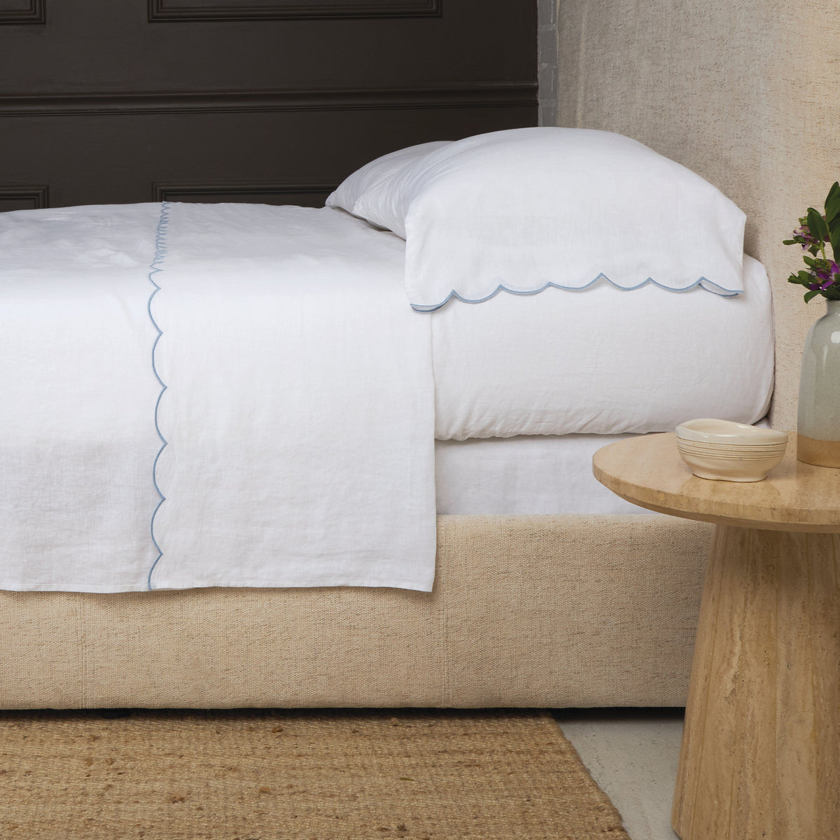 White linen sheet set with blue scalloped edge trim on flat sheet