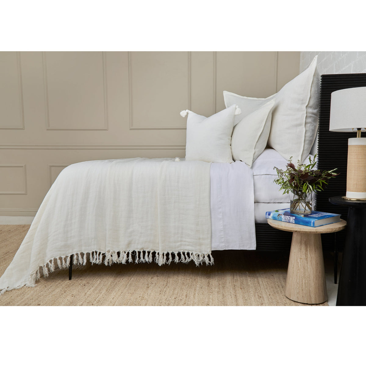 White textured blanket with fringed edge and matching throw pillows