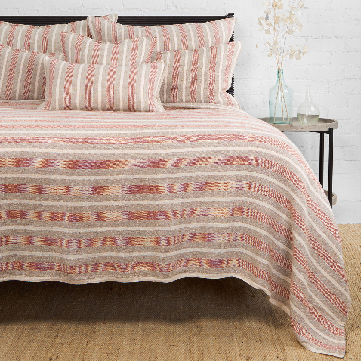 Striped throw blanket with coral and taupe bands, draped on bed