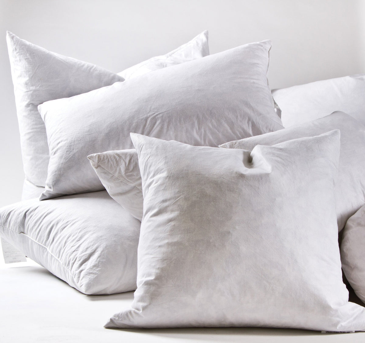 White pillow inserts with several cushions arranged on a couch