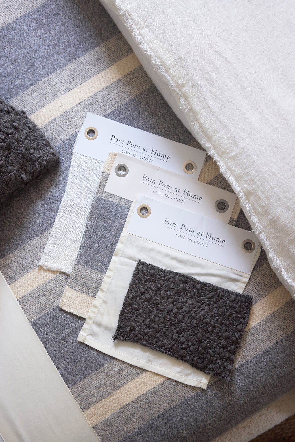 Striped blanket fabric swatch with stitched edge and brand tags, dark gray and blue stripes