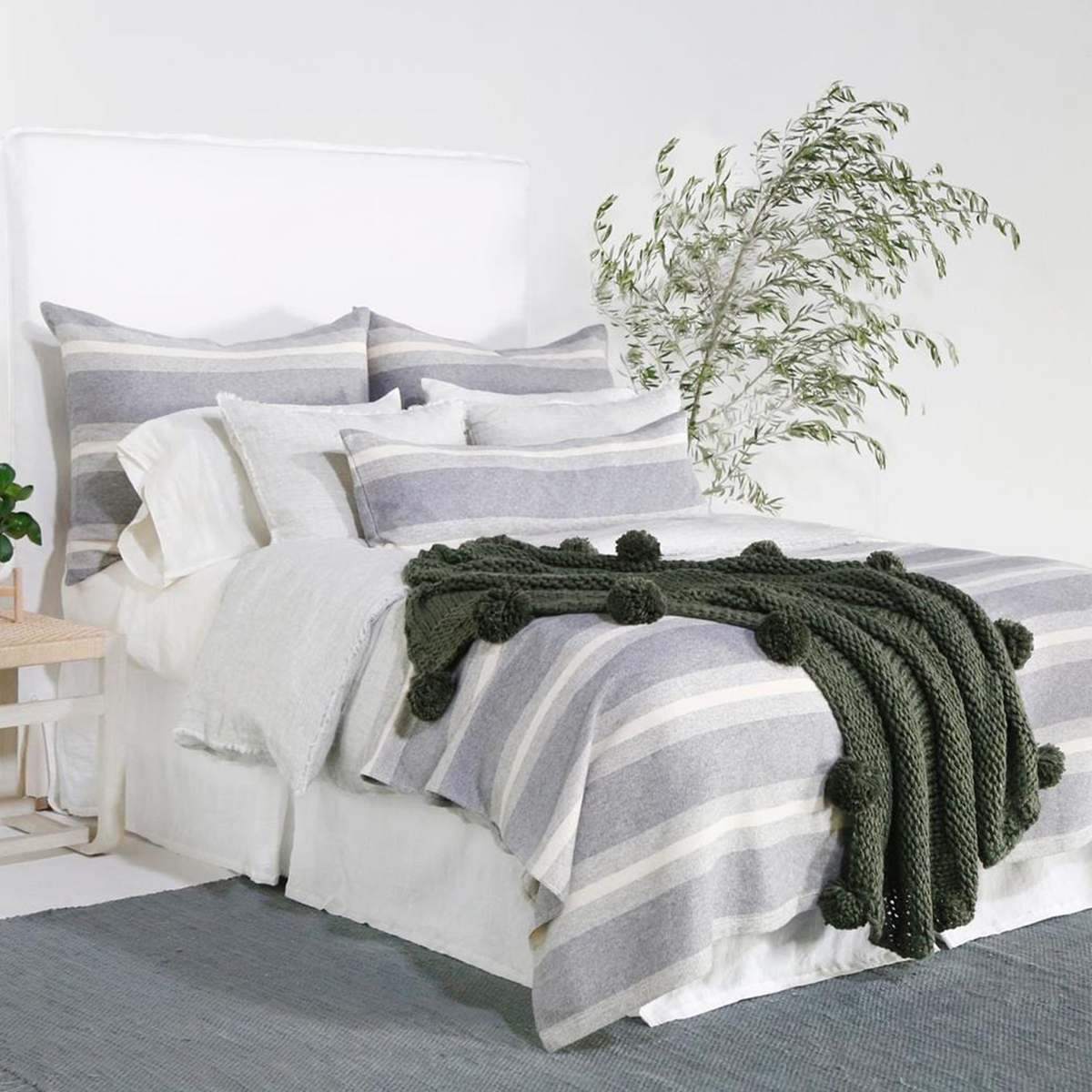Gray and light gray striped blanket folded on bed