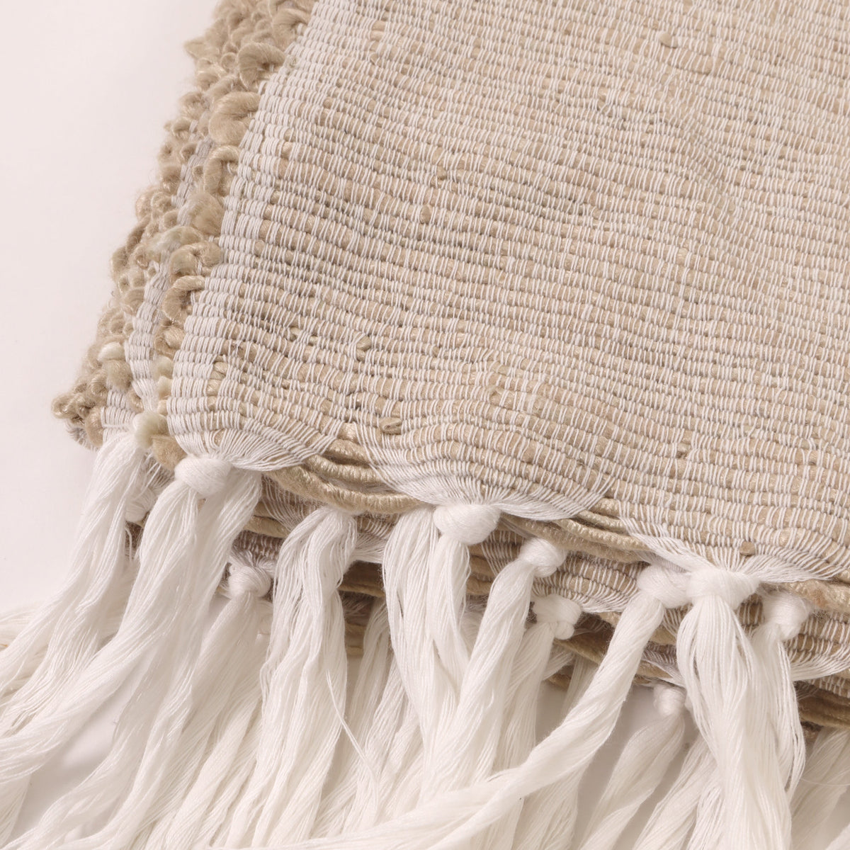 Natural throw close-up of woven fabric edge with white tassels and fringe