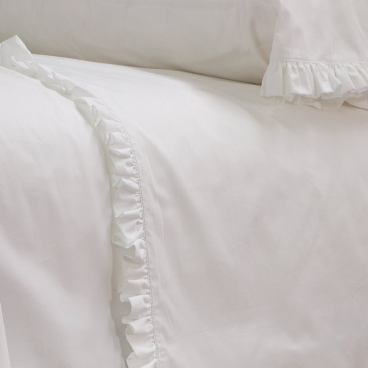 White cotton percale flat sheet edge with gathered ruffle trim and seams