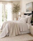 Decorative 28 x 36 square pillow with woven geometric pattern, shown on bed