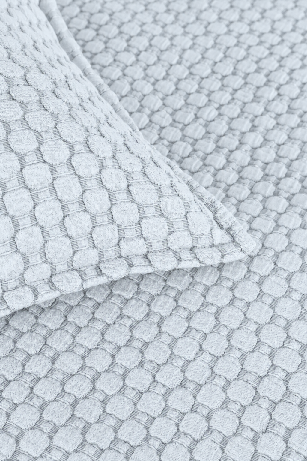 Matelasse quilted fabric close-up in light blue with repeating square pattern