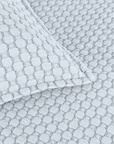 Matelasse quilted fabric close-up in light blue with repeating square pattern