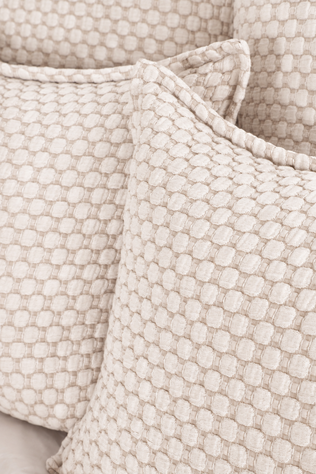 White matelasse bedding fabric with raised geometric texture close-up.