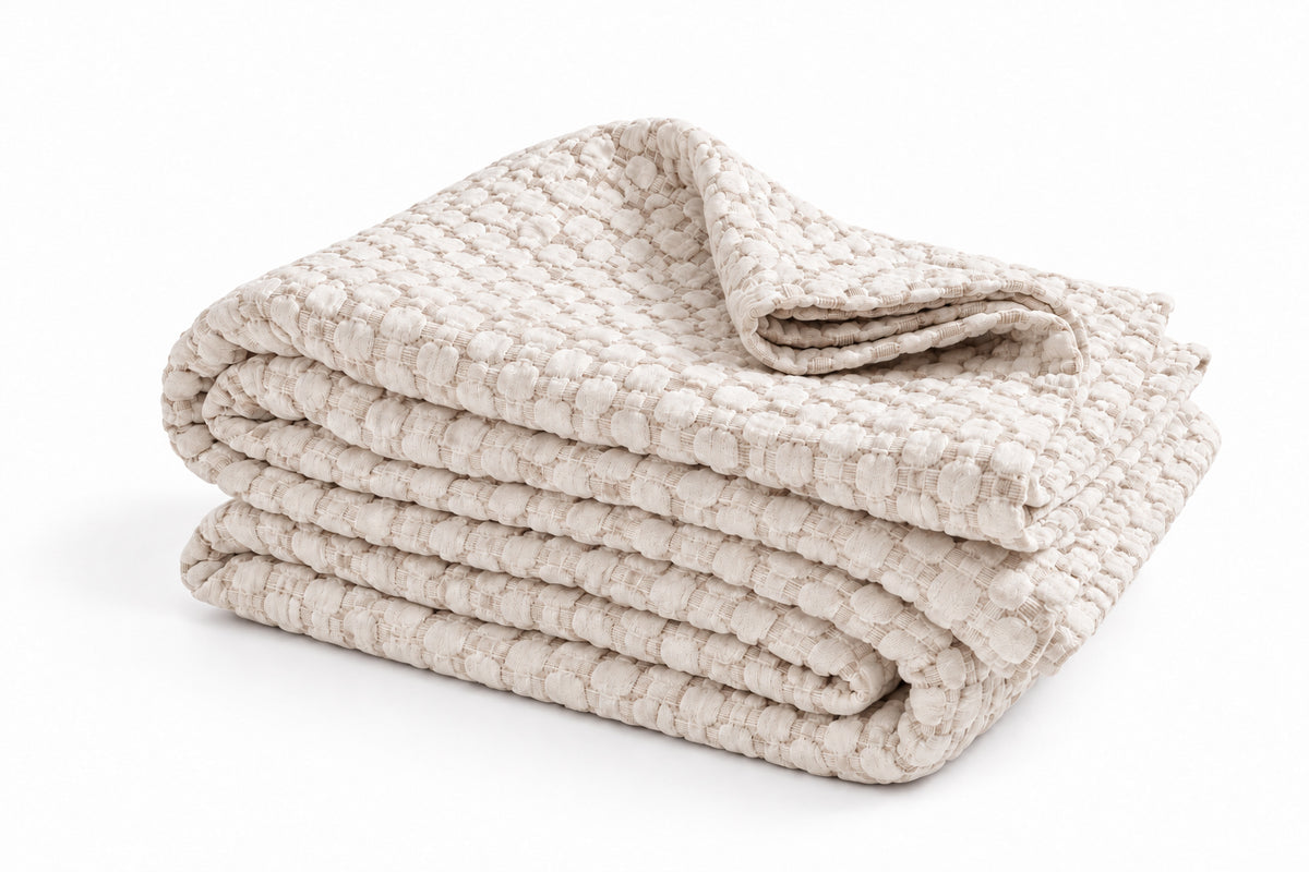 Folded white matelasse quilt with stacked layers and textured surface.