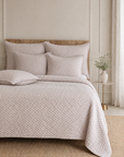 Oatmeal beige matelasse bedding set with quilt, shams, and pillows on a bed.