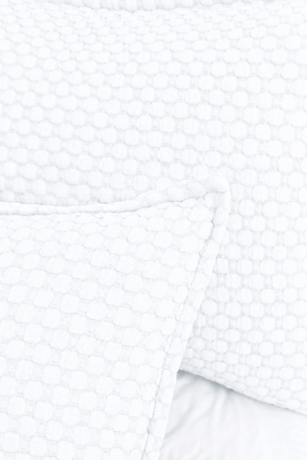 Close-up of white matelasse bedding with raised circle-and-grid texture.