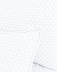 Close-up of white matelasse bedding with raised circle-and-grid texture.