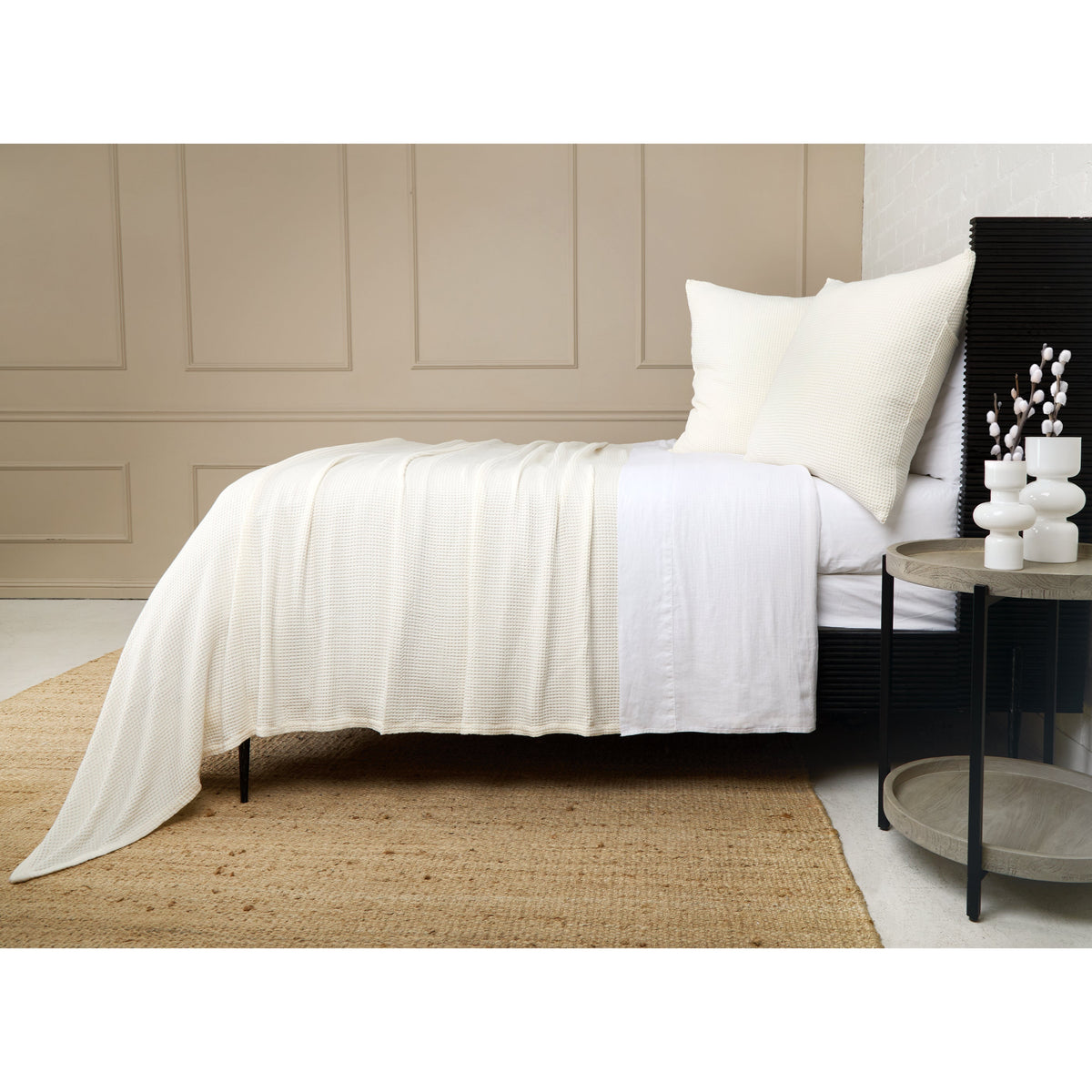 White textured blanket with pleated drape over bed, styled with matching pillows.