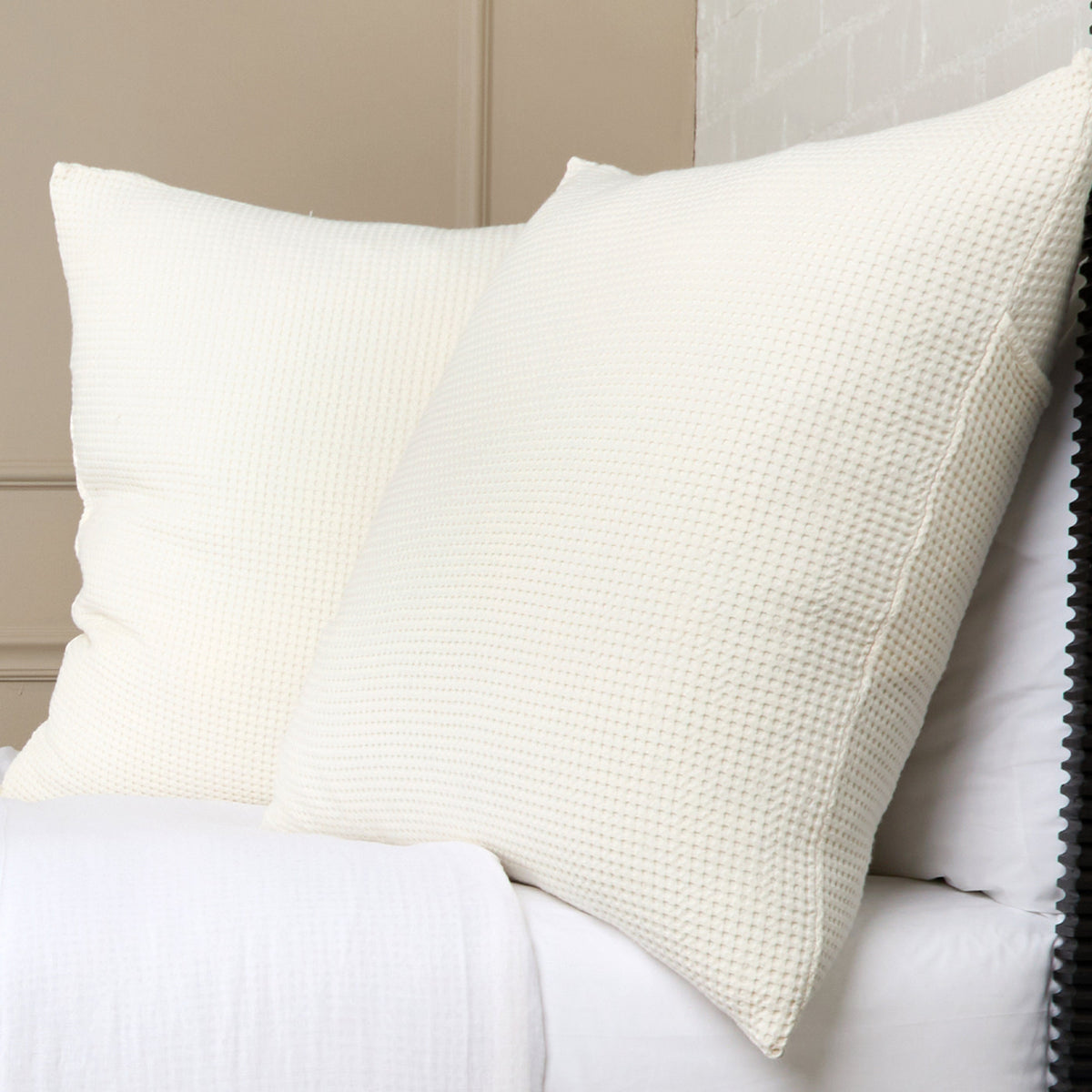 Ivory textured pillow on bed, featuring a woven waffle-like fabric texture.