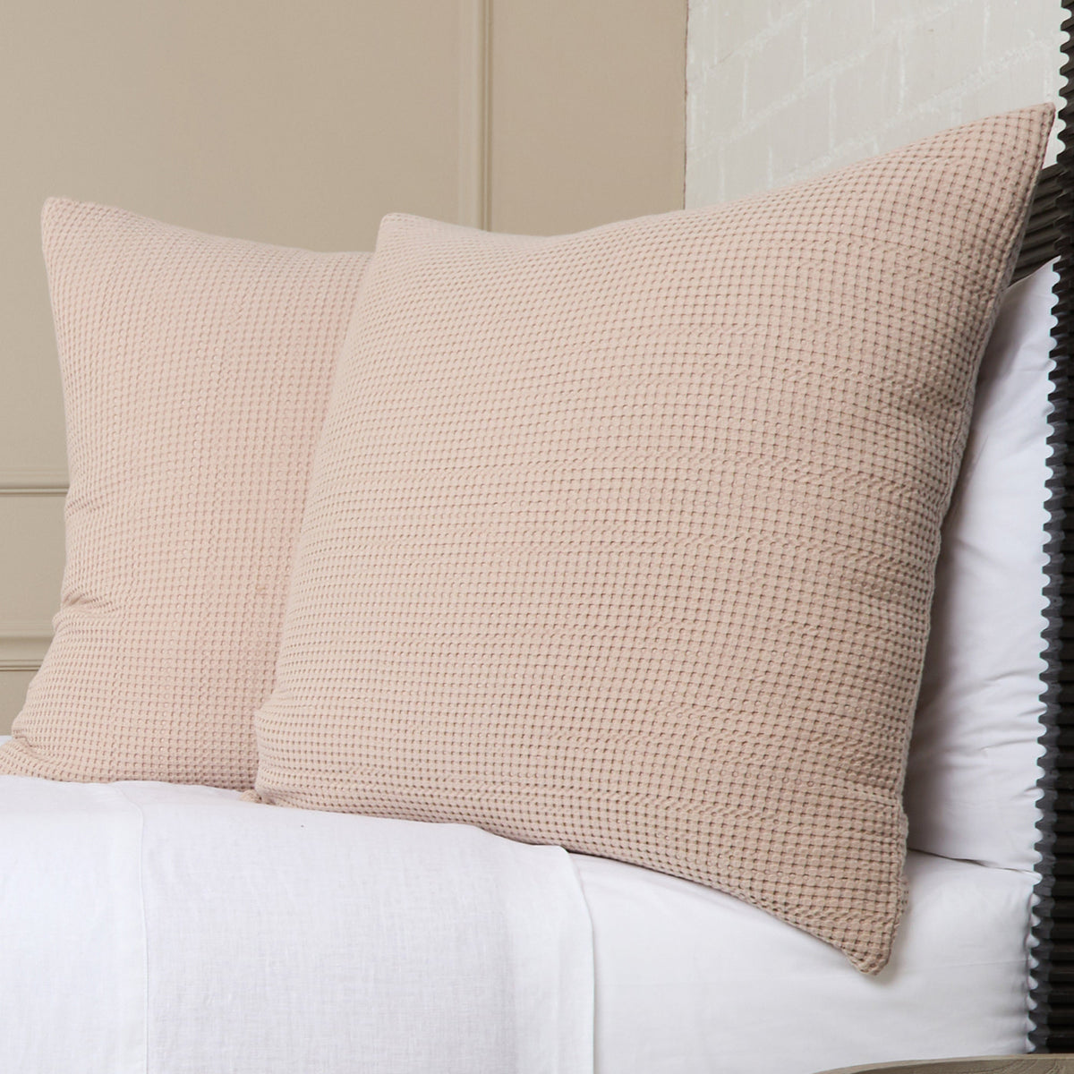 Beige textured pillow on bed, featuring a woven waffle-like fabric texture.