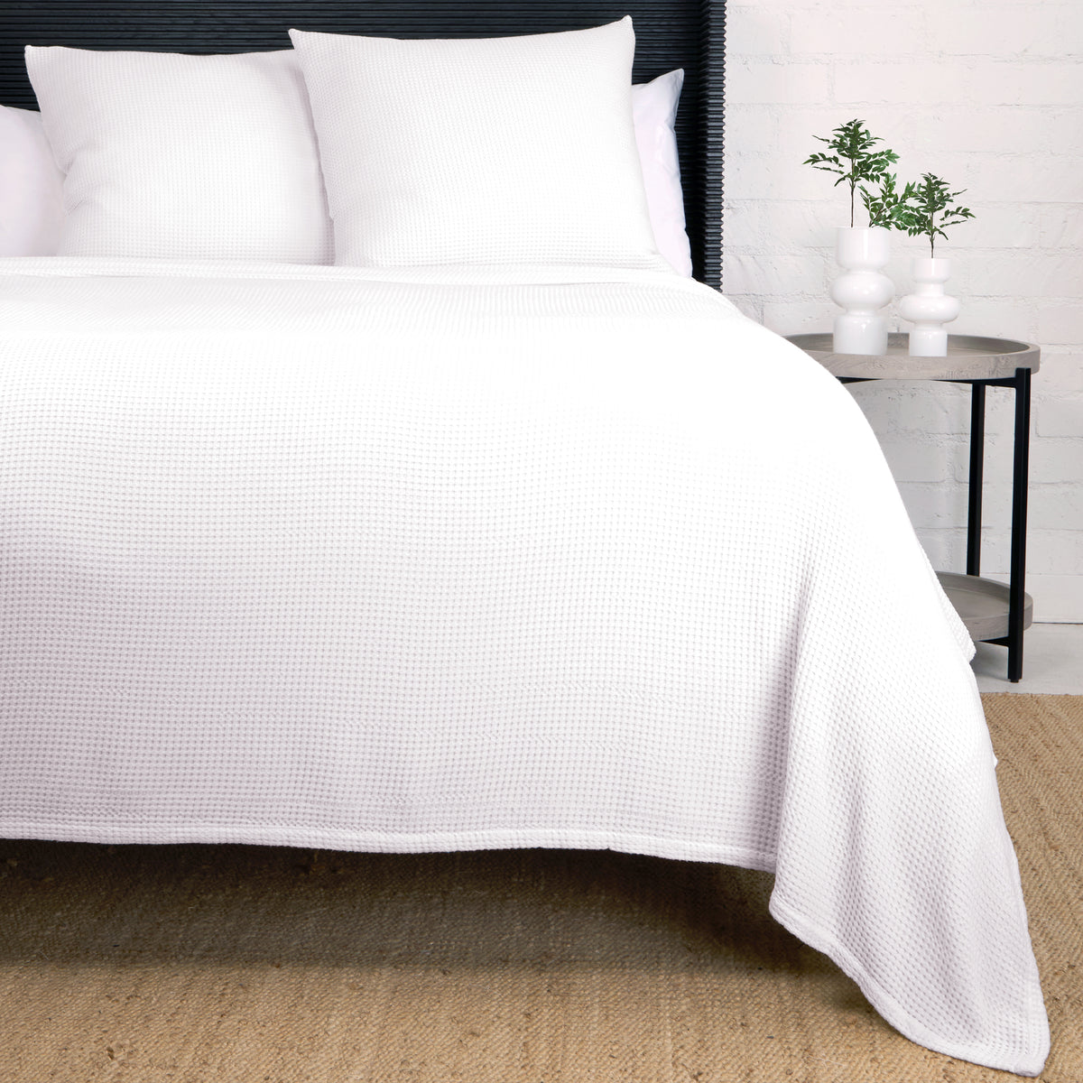 Balboa blanket in textured white weave, folded over bed with matching shams