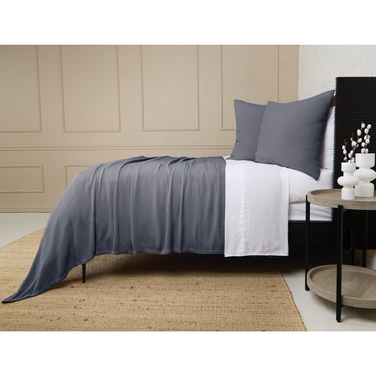 Blue-gray textured blanket with pleated drape over bed, styled with matching pillows.