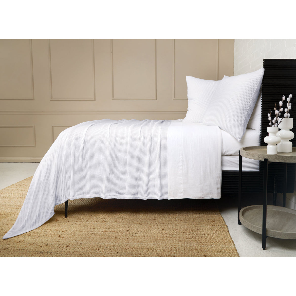 White textured blanket with pleated drape over bed, styled with matching pillows.