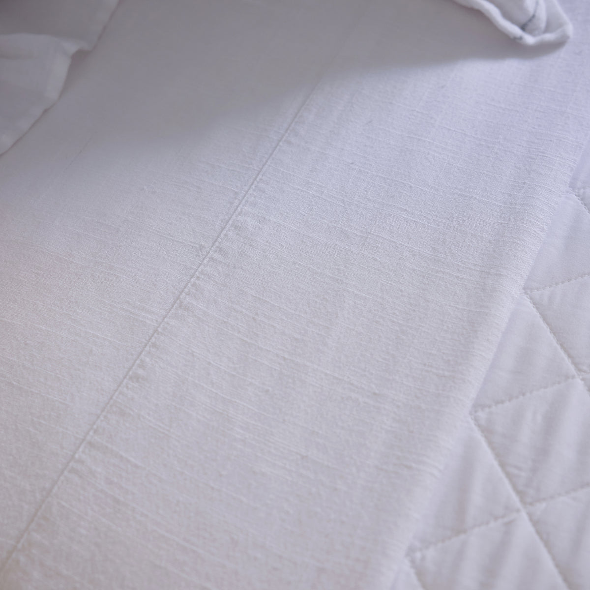 White bamboo linen sheet fabric with quilted panel and smooth woven texture.
