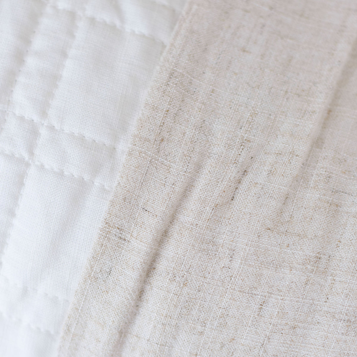 Natural bamboo linen sheet fabric close-up with subtle texture and stitching detail.