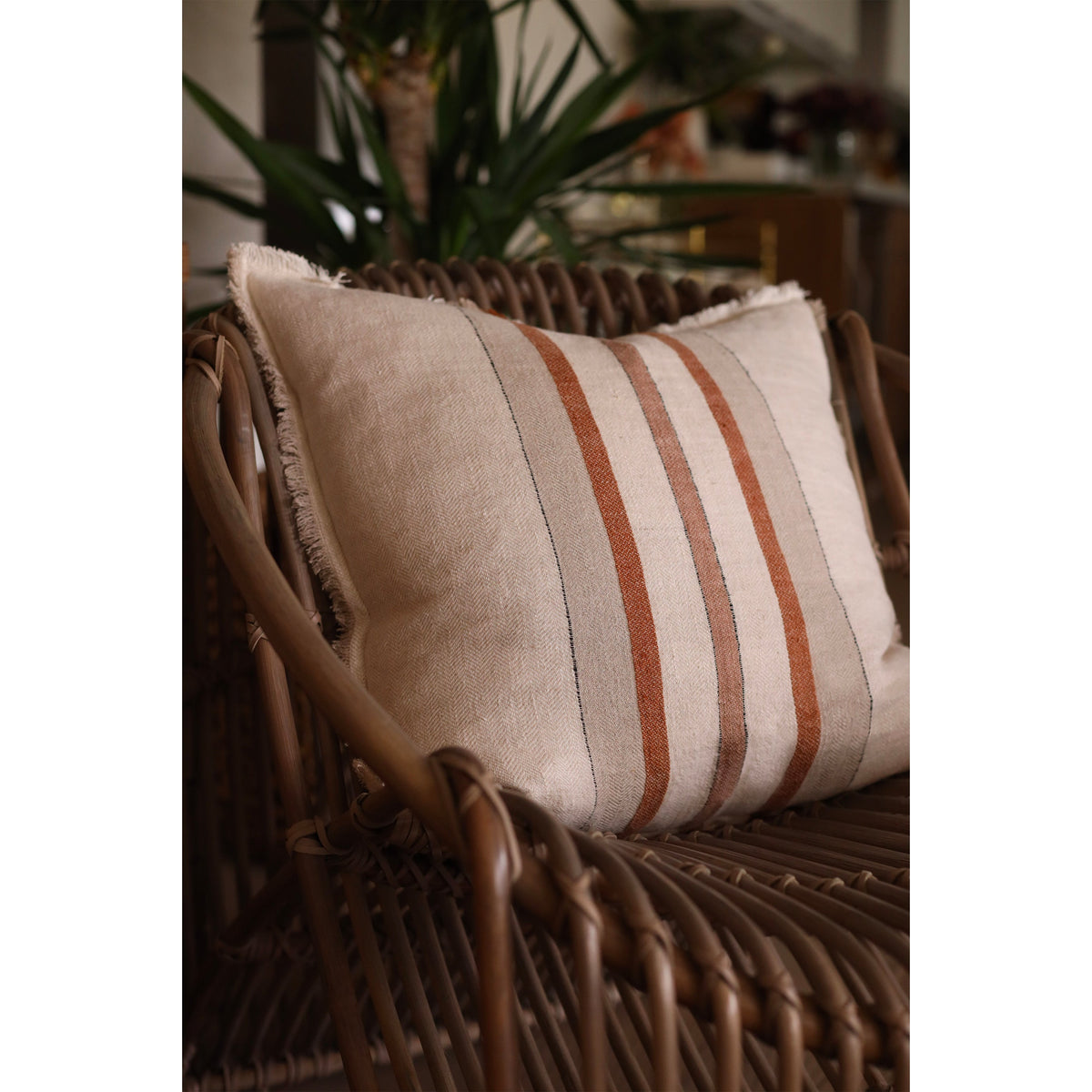 Rectangular beige pillow with vertical rust and white stripes on linen-textured cover