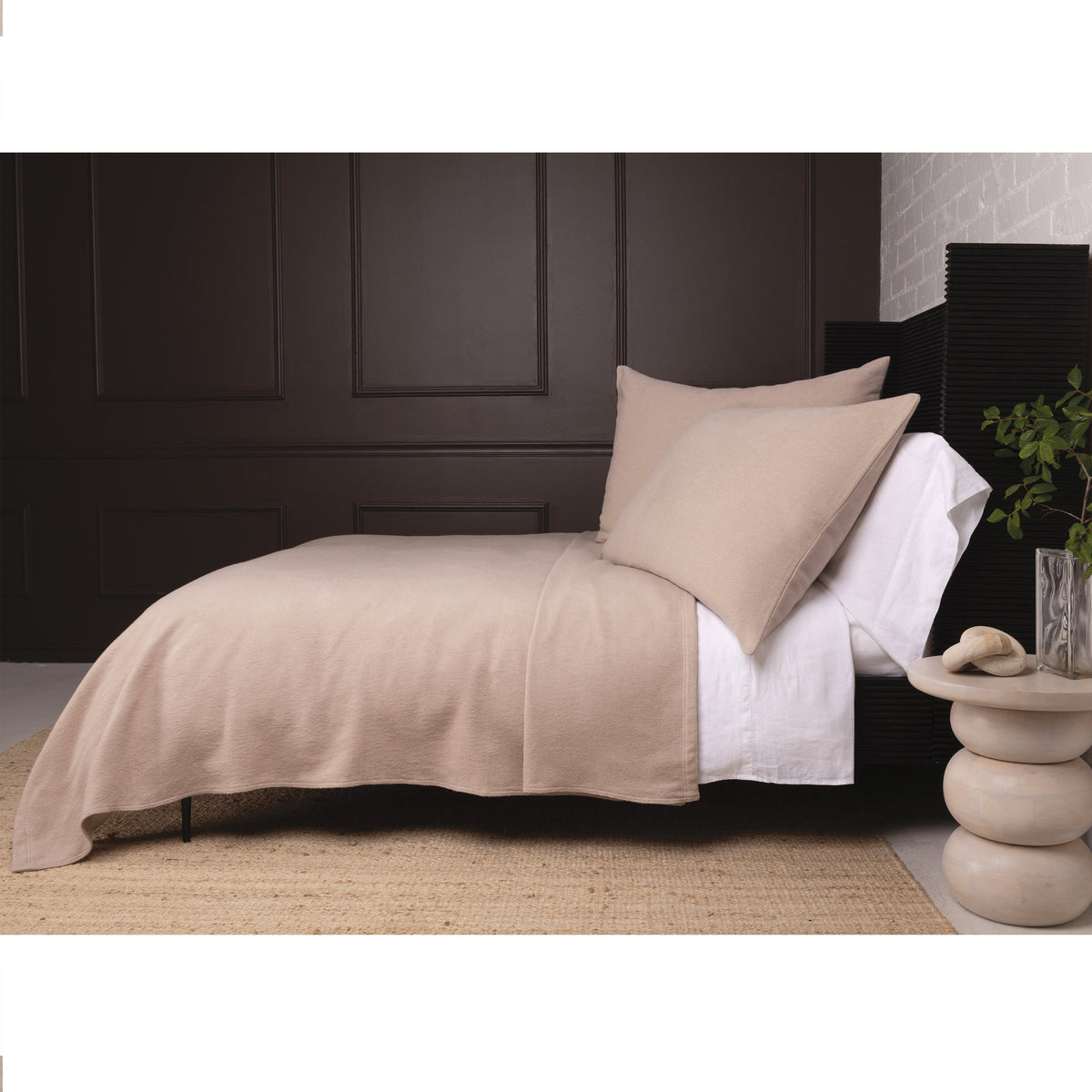 Taupe blanket laid across a bed with matching pillow
