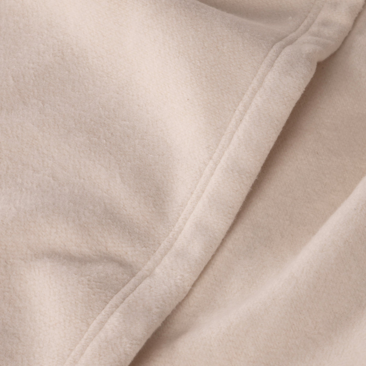 Ivory blanket seam detail with smooth, lightly textured fabric